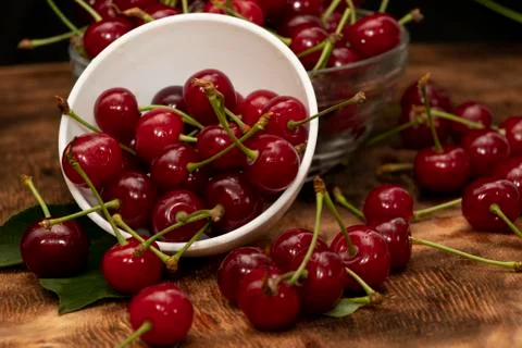 Red berries of a cherry in a white ceramic bowl. On a wooden background. A lo Stock Photos
