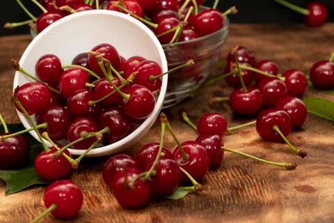Red berries of a cherry in a white ceramic bowl. On a wooden background. A lo Stock Photos
