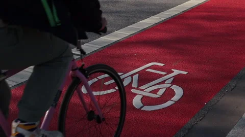Red bicycle path on which a bicycle passes close-up	 Stock Footage 311921986
