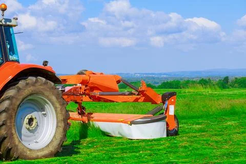 Red big mower mows the grass in the field. Preparation of silage for the wint Stock Photos