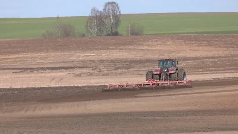 Red big twin wheels tractor with large plough ploughs the land Video stock 282197689