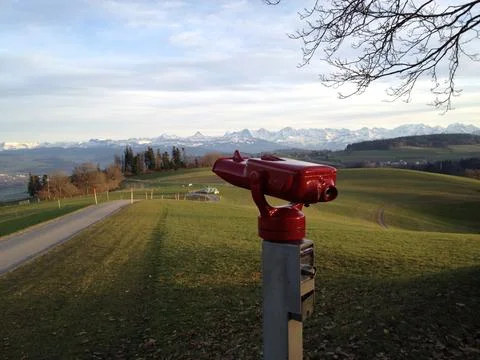 Red binoculars overlooking the bernese pre-alps toward the snow covered Stock Photos