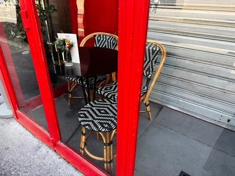 Red bistro window with black round table and wicker chairs at a Paris, Fran.. 库存照片