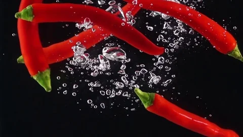 Red Bitter Cayenne Falling Through Water. Stock Footage 74552817