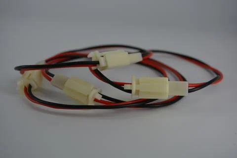 Red-black electrical cable with white plugs on a white background. Stock Photos