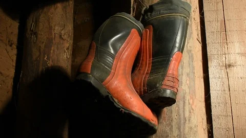 Red-black rubber boots on the wall of a wooden room, in the moving light of a la Stock Footage 122009926