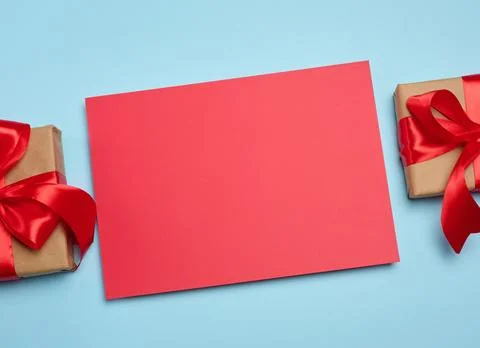 A red, blank rectangular sheet of paper between two craft-wrapped gift boxe.. Foto stock