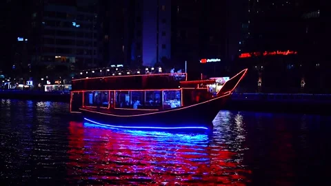 Red-blue ship sails on the canal at Dubai Marina surrounded by skyscrapers Stock Footage 220571685