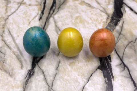 Red, blue, yellow Easter eggs. Three multicolored handmade easter eggs on a b Stock Photos