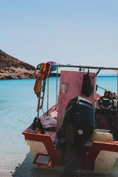 Red boat at the coast of a beach with crystal clear blue water Ensenada Grand Photos