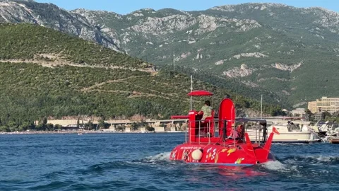 A red boat is floating on top of a body of water Stock Footage 283300862