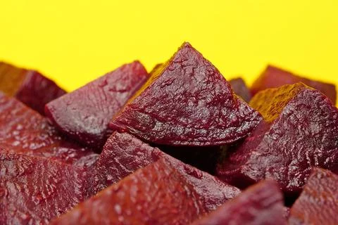 Red boiled beetroot cut into pieces on yellow background Фото
