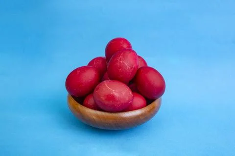 Red boiled easter eggs pile in a wooden bowl on blue background with copy spa Stock Photos