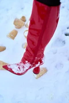 Red boot steps on an ice cream cone in the snow for surreal concept. High Stock Photos