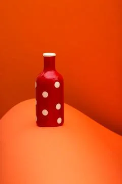 Red bottle on an abstract background of colored paper sheets Stock Photos