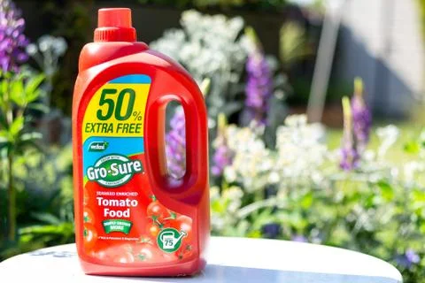 A red bottle of Go Sure Tomato feed on a white table in a garden setting Stock Photos