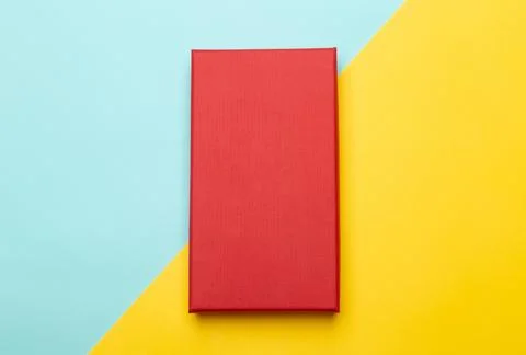 Red box product packaging isolated on yellow half blue background. Flat lay.. Stock Photos