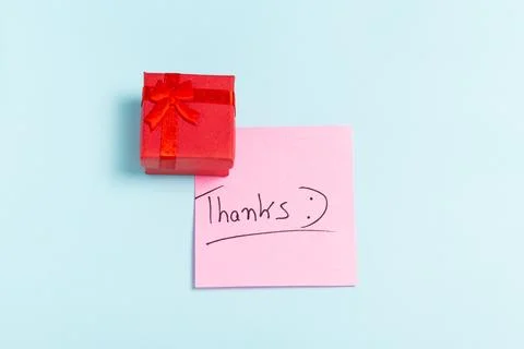 A red box with a red bow on top of a pink piece of paper that says "THANKS" Stock Photos