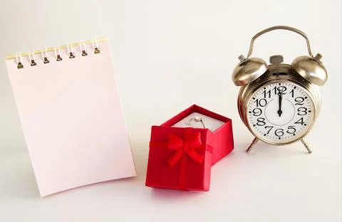 Red box of special gifts with a ring and a clock on a light background with a Stock Photos