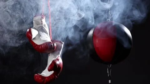 Red Boxing Gloves and Double end striking bag hang in surrounded by smoke. Stock-Footage 166605065