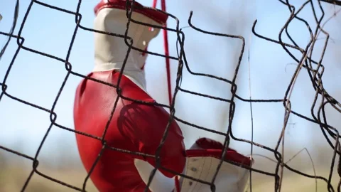 Red boxing gloves hanging on old metal fence. Vídeo Stock 105617686