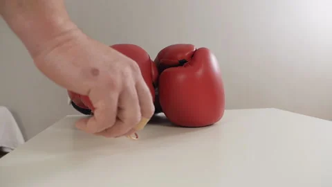 Red boxing gloves. A pair of red boxing gloves lies on a white table, a man's Vídeo Stock 144388310