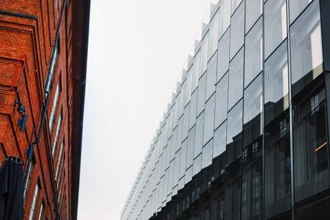 Red brick building alongside modern glass paneled structure Stock Photos