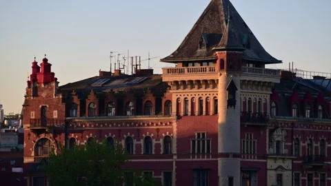 A red brick building with a corner tower and steep slate roof in early morning Video stock 342326403