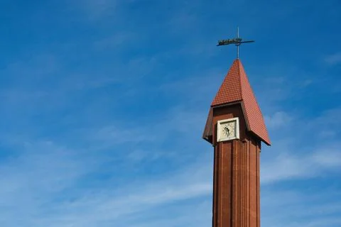 Red Brick Clock Tower Spire with Red Roof Against Blue Sky Stock Photos