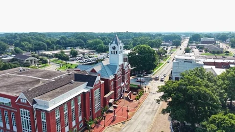 Red brick courthouse with white clock tower anchors small town square in Stock Footage 345100271