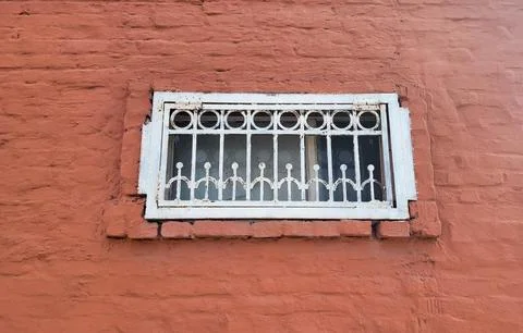 On the red brick facade there is a small rectangular window with a white wr.. Stock Photos
