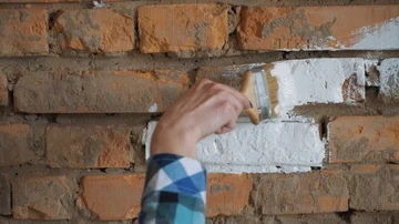 Red brick paint in white. In the hands of girls paint brush. The girl makes Stock Footage 85809634