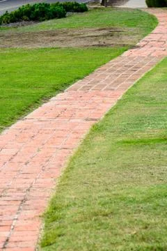 Red brick path crosses grass Foto stock