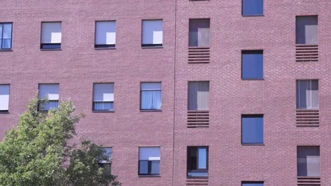 Red brick residential building facade with repeating window pattern Stock Footage 336384448