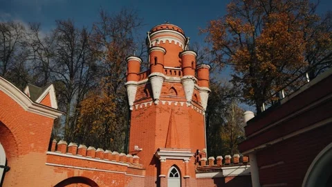 A red brick tower and autumn trees with falling leaves are in the frame. Stock Footage 312728257