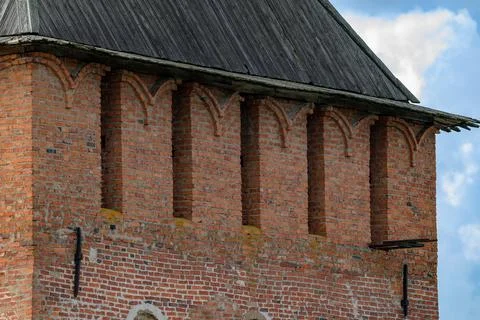 Red brick tower with arched openings and tiled roof. Weathered surface show.. Stock Photos