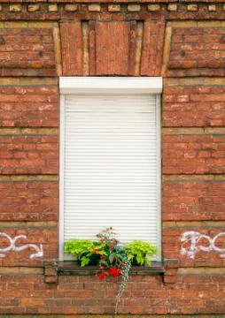Red brick wall and window with rolling shutters Foto stock