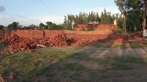Red brick wall construction site with building materials in an open field Vídeo Stock 347256712