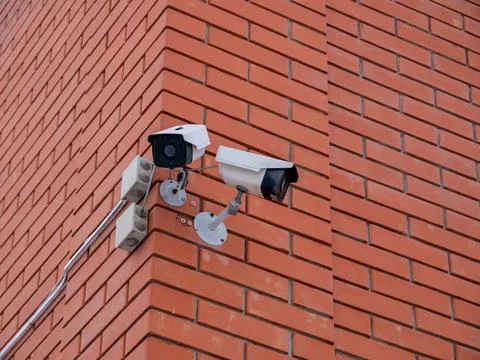 Red brick wall corner with video camera security system Stock Photos