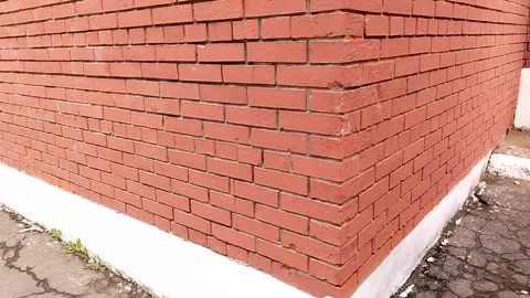 Red brick wall corner with white base, showing texture and pattern of bricks, Stock Footage 329428707