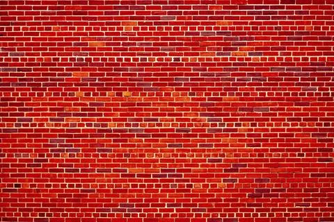 Red brick wall creates bold background. Red masonry texture supports industrial Stock Photos