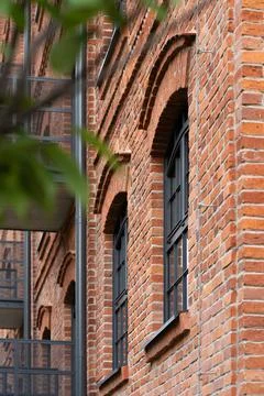 Red brick wall facade of loft apartment building with arch windows Stock Photos