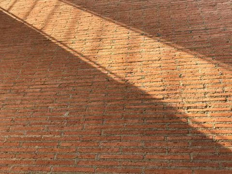 Red brick wall with light shadow crosses on it in wide diagonal shape Stock Photos