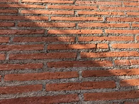 Red brick wall with light shadow crosses on half of it in diagonal shape Stock Photos