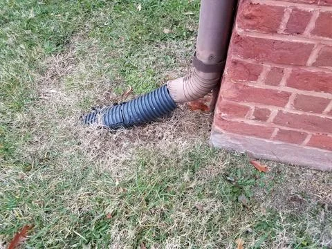 Red brick wall or masonry with gutter downspout and grass Stock Photos