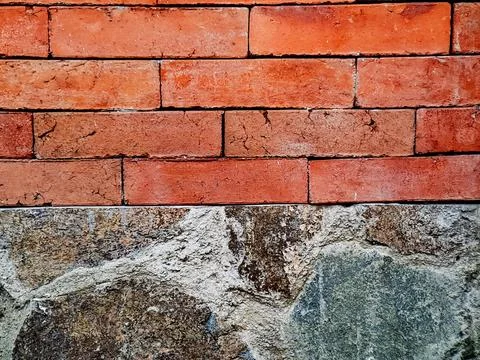 Red brick wall rises above a grey stone foundation showing textures and arc.. Stockfoto's
