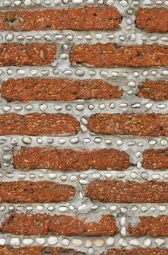 Red brick wall with small white rocks. Stock Photos