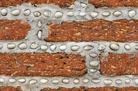 Red brick wall with small white rocks. Stock Photos