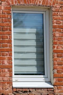 Red brick wall surrounds white window frame Stock Photos