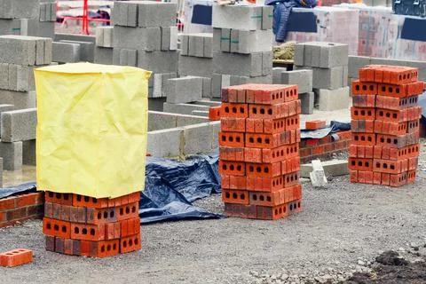 Red bricks and concrete blocks delivered on construction site and placed next Stock Photos